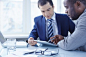 Image of two young businessmen discussing data in touchpad at meeting