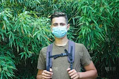 户外徒步少年用竹藤底部和背包和外科口罩，在公共场所保护