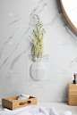 在时尚的浴室里，白色大理石墙壁上有硅胶花瓶和鲜花