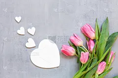 一束粉红色的郁金香和木制的心形图案。概念为情人节、妇女节和其他浪漫事件。俯视图，特写，平躺在白色木质