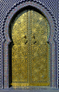 Islamic door carved in gold with surrounding mosaic tile.