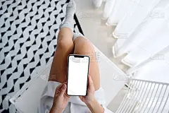 女人拿着手机与空白桌面白色屏幕坐在卧室，感觉轻松