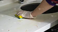 戴着手套用海绵擦拭厨房的人