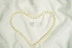 白色绸布上心形的珍珠珠。情人节、妇女节或婚礼的背景。贺卡模板