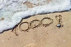 海滩上的数字1000。社交媒体上的里程碑帖子。
