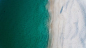 Drone view of a clear ocean washing up on sand shore in Nelson Bay