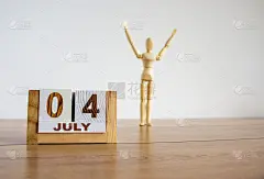 创意形象独立日。木制日历，日期为7月4日。木制人体模型放在漂亮的木桌上。