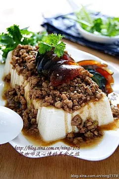 材料
内酯豆腐  1盒
猪肉馅  约80克
酱油  
鸡精  适量
香菜末  
皮蛋  2个
生抽  
五香粉  少许
水淀粉  适量
葱姜末  
作法
1.用剪刀减去内酯豆腐盒的4个底边，这样处理可以很轻松倒出完整的内酯豆腐；
2.把内酯豆腐倒入盘中，沥出多余的水分，放微波炉大火加热1分钟（时间根据自家微波炉功率适当调整）备用；
3.皮蛋剥壳后洗净，切成薄片或者小粒；
4.把切好的皮蛋码在内酯豆腐上；
5.炒锅倒油烧热，下葱姜末、五香粉爆香，再放入肉香炒熟；
6.倒入生抽酱油，用量自己掌握；
7.再放鸡