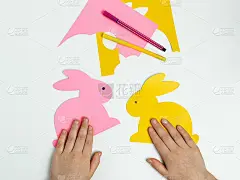 一个孩子用纸剪出复活节兔子。为节日做准备，为孩子们做手工艺品。俯视图