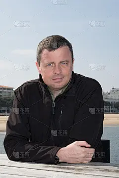 英俊的男人站在沙滩上，望着大海，穿着秋暖气爽的外套