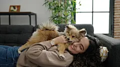 点击来源直接获取大图文件 |Young hispanic woman with dog lying on sofa playing at home