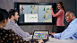 Woman using pinch and zoom on Microsoft Surface Hub screen while two men watch