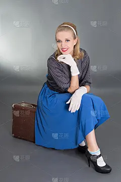 年轻漂亮的海报女郎坐在复古行李箱上