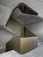 Concrete and brass staircase with a Brutalist feel. Visit houseandleisure.co.za for more