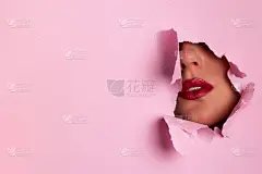 明亮的嘴唇透过孔在粉红色的纸背景。化妆师，美的概念。准备参加新年晚会。化妆品销售。美容院广告横幅，有
