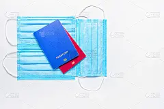 两本蓝色和红色的外国护照，佩戴医用口罩，背景为浅色。世界隔离的概念。平的。本空间