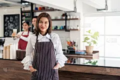 女店主的肖像站在她的咖啡店门口，展示了打开的招牌