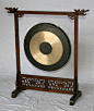 Metal gong set on a carved wooden stand.