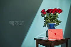 Window light shining on a dozen red roses and card