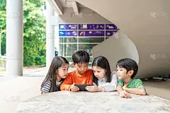 一群亚洲孩子一起在智能手机上玩游戏，微笑的小弟弟和小妹妹玩手机，看有趣的卡通。儿童与科技概念
