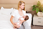 A young mother breastfeeding her little baby girl while holding in her arms