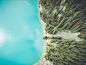 A drone shot of a rocky wooded shore of a blue lake