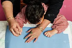 特殊教育的老师和学生穿着长袍，在桌子上用手画着生日花环和涂着丙烯颜料的黄色纸板。塑料工艺疗法。