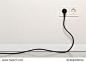 Black power cord cable plugged into european wall outlet on white plaster wall with copy space