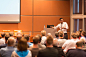Business speaker giving a talk in conference hall.
