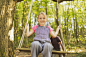 Portrait smiling girl swinging on rope swing in forest by Caia Images on 500px