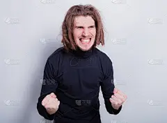 一名愤怒的男子咬紧牙关，双手握紧拳头靠近胸部，身穿深灰色高领毛衣，头戴短发。隔离在灰色背景，复制空间