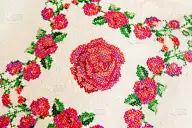 装饰元素，十字绣玫瑰花，在白色亚麻布织物上。绣花机,特写。