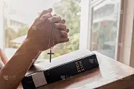 美丽冷静的女孩闭着眼睛在圣经上祈祷。