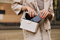 Photo cropped photo of young woman walking outdoors put her mobile phone to bag.
