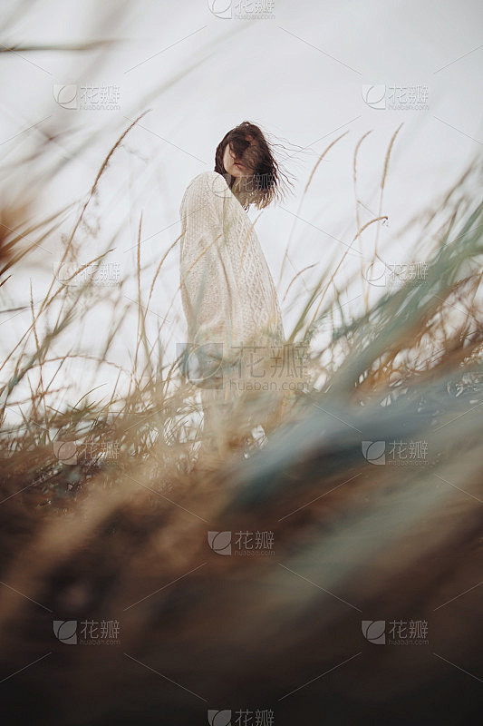 美丽时尚的女人与风的头发在针织毛衣摆姿势...