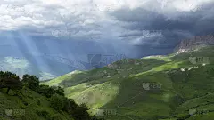 山脉上空乌云密布。阳光照亮了草地。全景景观。健美的。