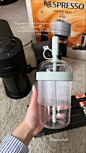 This may contain: a person is holding a glass jar with water in it on the floor next to a coffee maker