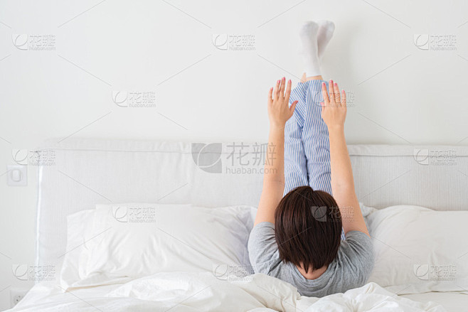 女人双腿高高地躺在床上做运动