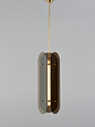 In this statement pendant, a trio of elongated tinted glass or brushed brass panels encase a custom-made glass lighting tube, finished with brass detailing.