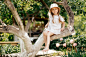 小女孩在夏天的花园里爬树,活动.小女孩在树枝上，童年时代。假期，活动，生活方式。童年时代的时尚、风格