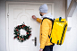 Delivery Man Knocking on Door with Christmas Wreath