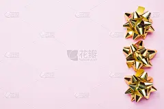 粉红色背景上的金色圣诞蝴蝶结。礼物概念问候节日生日婚礼新年圣诞节母亲节。副本的空间。