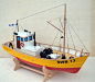 This may contain: a small yellow and red boat sitting on top of a white table next to a wall
