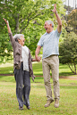 一对活跃的老年夫妇手牵着手在公园里跳跃