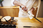 A chef working in a small commercial kitchen, an itamae or master chef preparing to make sushi, cleaning his knife.