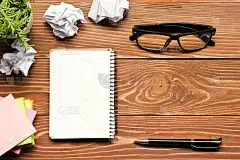 办公桌子，桌子上放着办公用品和皱巴巴的纸张。俯视图