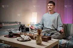 一位中国传统茶艺大师在等待泡茶的同时，在家中冥想