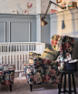 A floral armchair and footstool next to a baby’s cot, with clamp light above.
