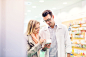 Male pharmacist serving a female customer.