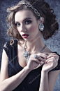 Young, luxurious, romantic girl with curly hairstyle wearing silver, shiny jewellery. She has got gold and purple makeup with red lips.